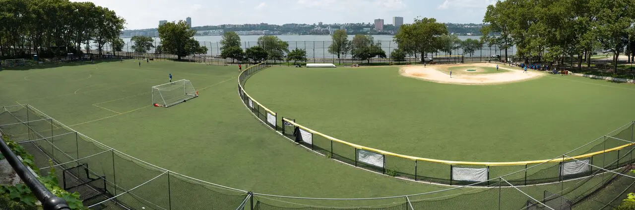 A baseball field with a fence and water in the background.