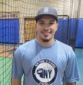 A man in blue shirt and hat standing next to a net.