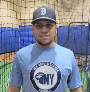 A man in blue shirt and hat standing next to a net.