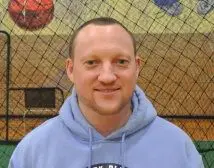 A man in blue hoodie standing next to a net.