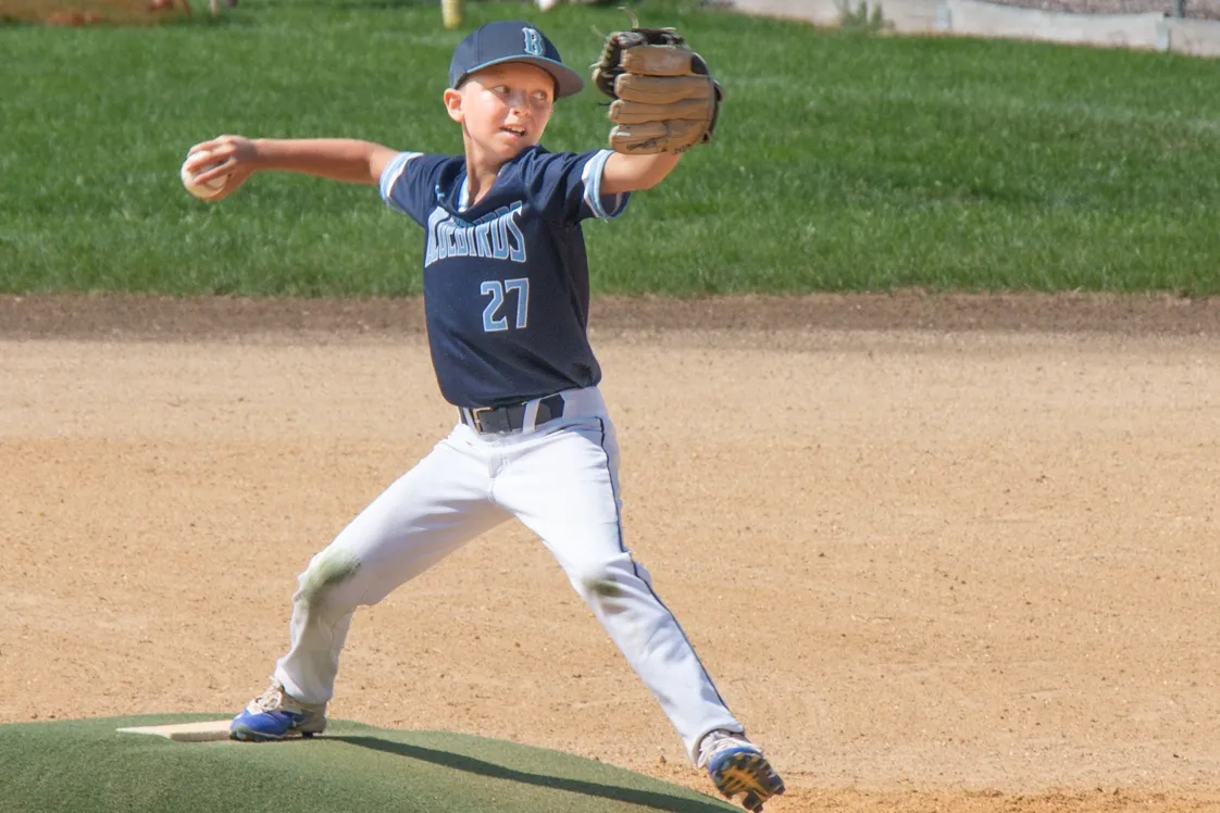 A young baseball player is throwing the ball.