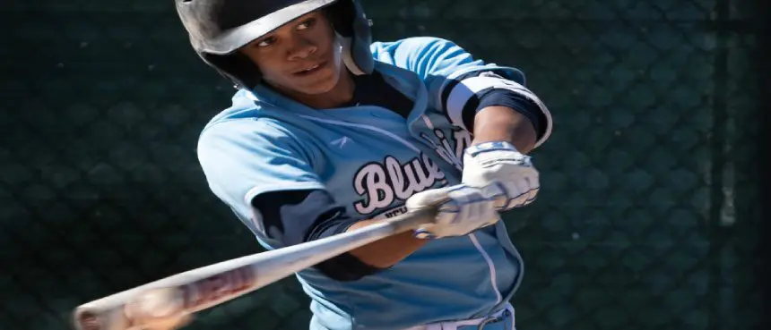 A baseball player swinging at the ball with his bat.
